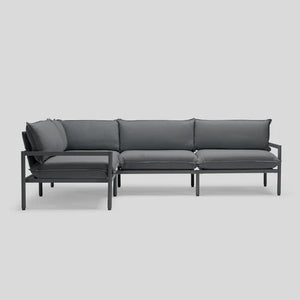 The Terra Sectional is a contemporary outdoor sofa featuring a sleek, dark gray finish with a sturdy metal frame and cushioned seats and backrests, all showcased against a simple light gray background.