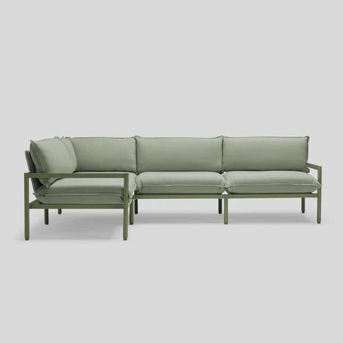 Introducing the Terra Sectional: a minimalist green sofa with a metal frame, featuring cushioned seats and backrests, elegantly displayed against a plain gray background.