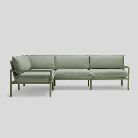 Introducing the Terra Sectional: a minimalist green sofa with a metal frame, featuring cushioned seats and backrests, elegantly displayed against a plain gray background.