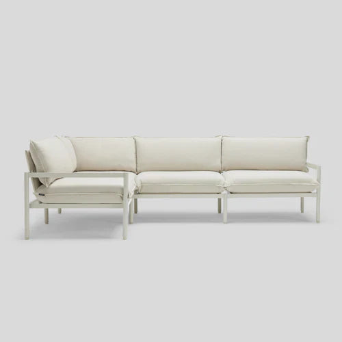 The Terra Sectional, a modern and minimalist white sofa with cushions, is displayed against a plain light-gray background. It features clean lines and a simple design, making it ideal for contemporary interiors.