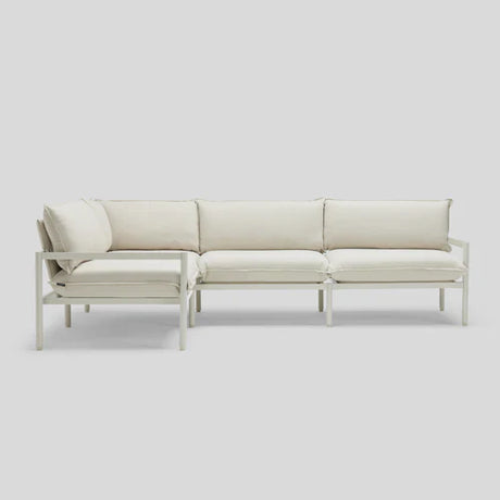 The Terra Sectional, a modern and minimalist white sofa with cushions, is displayed against a plain light-gray background. It features clean lines and a simple design, making it ideal for contemporary interiors.