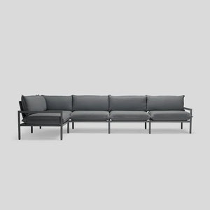 The Terra Sectional is a contemporary, minimalist sofa featuring a dark gray metal frame and coordinating dark gray cushions, designed in an L-shape against a light gray backdrop.