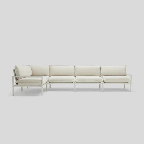 The Terra Sectional, featuring a minimalist design with white cushions and a sleek metal frame, is set against a plain light gray background.
