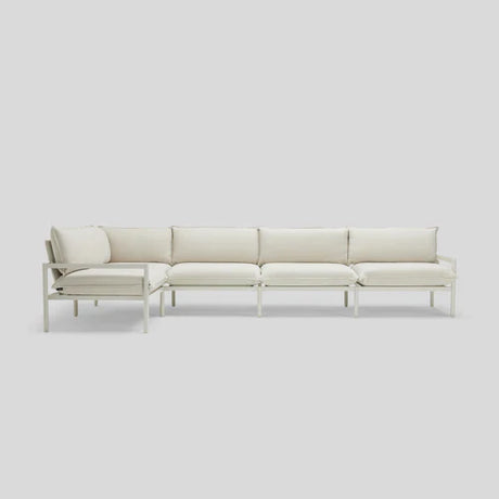 The Terra Sectional, featuring a minimalist design with white cushions and a sleek metal frame, is set against a plain light gray background.