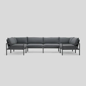 The Terra Sectional, characterized by its modern and minimalist design with a dark gray hue, metal frame, and cushions, is showcased against a plain light gray background.
