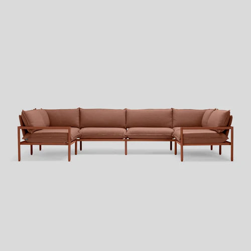 The Terra Sectional is a minimalist brown sofa featuring thin wooden frames and comfortable cushions, elegantly showcased against a plain gray background.