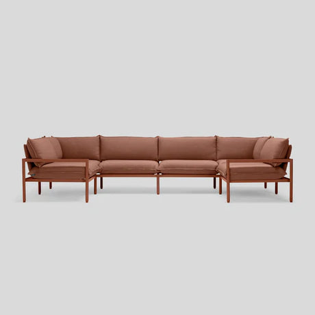 The Terra Sectional is a minimalist brown sofa featuring thin wooden frames and comfortable cushions, elegantly showcased against a plain gray background.