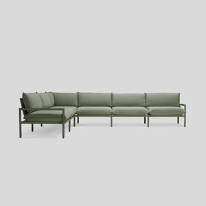 The Terra Sectional is a spacious L-shaped sofa with a minimalist design, showcasing a green metal frame and complemented by green cushioned seats and backrests. It is elegantly displayed against a plain light gray background.
