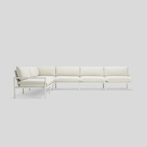 The Terra Sectional, a minimalist L-shaped sofa with a metal frame and plush white cushions, is set against a plain light gray background. The sofa consists of three sections that create a corner seating arrangement.