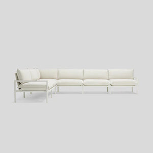 The Terra Sectional, a minimalist L-shaped sofa with a metal frame and plush white cushions, is set against a plain light gray background. The sofa consists of three sections that create a corner seating arrangement.