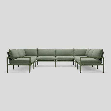 The Terra Sectional is a green L-shaped sofa featuring a sleek metal frame and plush cushions, set against a light gray background. Its minimalist design boasts straight lines and offers comfortable seating for multiple people.