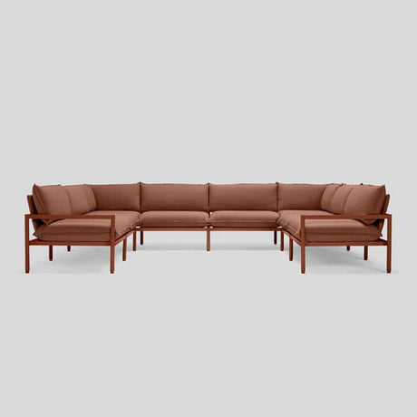 The Terra Sectional is a minimalist brown L-shaped sofa featuring a wooden frame and plush cushions, set against a plain gray background.