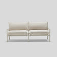 A minimalist Terra Loveseat featuring a white design, metal frame, and plush cushions is set against a light gray background.