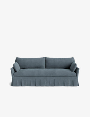 Introducing the Portola Pleated Sofa: a luxurious teal-colored piece featuring two large cushions and two side pillows. Its classic and elegant design is enhanced by a pleated skirt at the base, all set against a plain white background.
