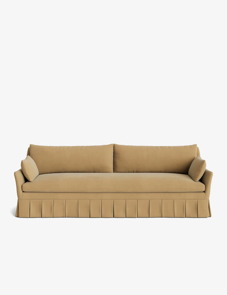 The Portola Pleated Sofa, featuring a beige design with a pleated skirt, comes complete with two long cushions and two cylindrical bolster pillows on each side, all set against a white background.