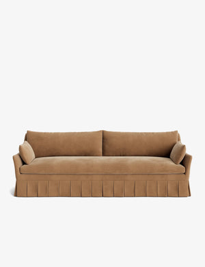 Presenting the Portola Pleated Sofa: A minimalist design featuring rich brown velvet, two cylindrical side cushions, and a pleated skirt, perfectly highlighted against a plain white background.