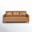 The Portland 80.5" Leather Sofa is a mid-century modern style piece featuring three seat cushions, three back cushions, and straight armrests in brown leather. It is supported by wooden legs and displayed against a plain white background.
