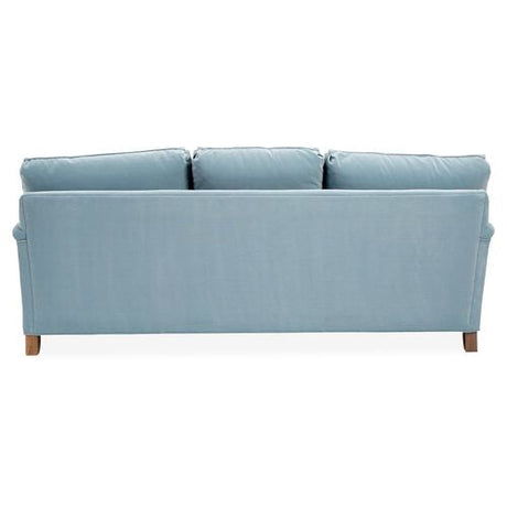 Back view of the Brooke 6-Seat Sofa in light blue upholstery featuring three cushions and wooden legs, set against a white background.