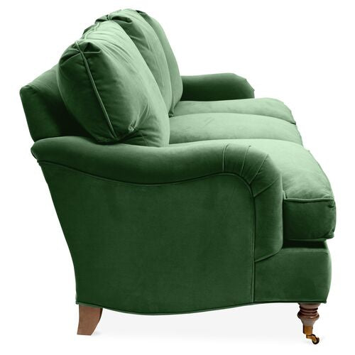 A side view of the Brooke 6-Seat Sofa in plush green velvet showcases its classic design with two large back cushions and rounded armrests, resting on wooden legs against a white background.
