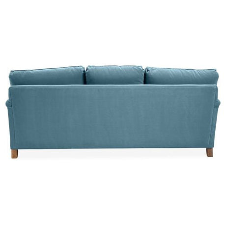 A Brooke 6-Seat Sofa featuring a blue design with three cushioned backrests, seen from behind. It boasts a simple design complemented by wooden legs.