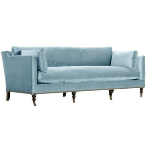 The Margot Velvet Sofa is a light blue piece with plush cushions and dark wooden legs, showcasing a modern design with a high back and armrests.