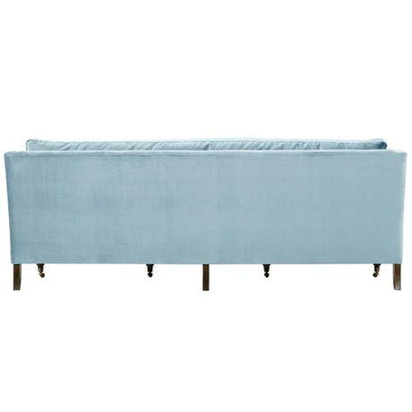 The Margot Velvet Sofa, in a light blue hue, showcases a rectangular design when viewed from the back. It features a high backrest and wooden legs that contribute to its modern and elegant look.