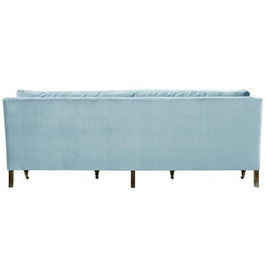 The Margot Velvet Sofa, in a light blue hue, showcases a rectangular design when viewed from the back. It features a high backrest and wooden legs that contribute to its modern and elegant look.