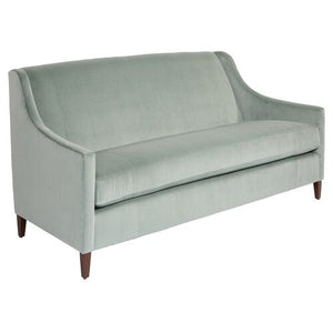 The Dawes Sofa in Sage Velvet features a mid-century modern design with clean lines and wooden legs. It includes a smooth, cushioned back and seat, along with slightly curved armrests for an elegant and simple look.