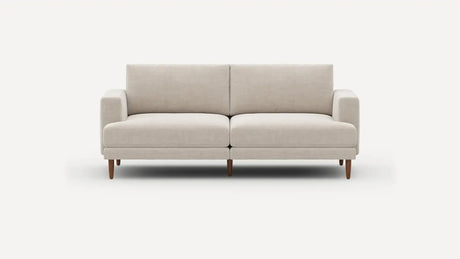 Introducing the Ember Mid-Century Modern 75" Sofa— a contemporary light beige piece showcasing clean lines and a minimalist design. This sofa features two seat cushions and two back cushions, complemented by low armrests and wooden legs, all set against a plain white background.