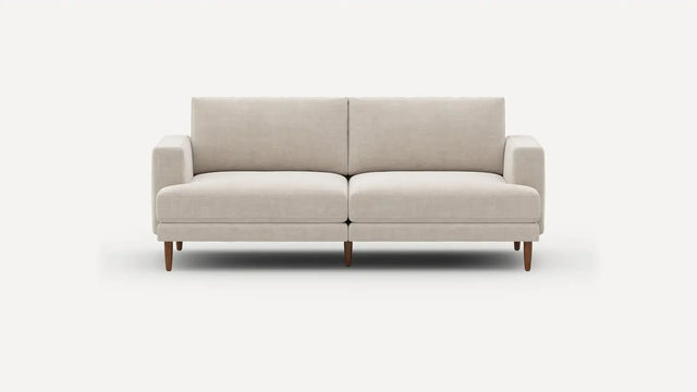 Introducing the Ember Mid-Century Modern 75" Sofa— a contemporary light beige piece showcasing clean lines and a minimalist design. This sofa features two seat cushions and two back cushions, complemented by low armrests and wooden legs, all set against a plain white background.