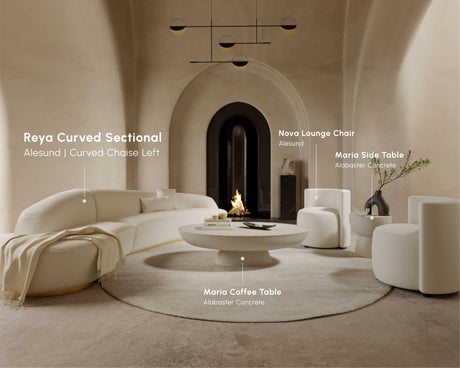 A contemporary living room with arched walls showcases the Reya Curved Sectional, complemented by a Nova lounge chair, Maria coffee table, and Maria side table, all in soothing neutral shades. The space is further enhanced by a minimalist fireplace and stylish lighting that exude warmth and sophistication.