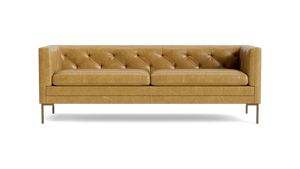 The Sit Tight 90" Sofa in tan leather showcases a tufted backrest and seat cushions. Its minimalist design is highlighted by clean lines and sturdy metal legs, set against a solid black backdrop.