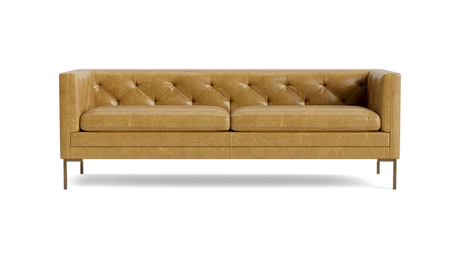 The Sit Tight 90" Sofa in tan leather showcases a tufted backrest and seat cushions. Its minimalist design is highlighted by clean lines and sturdy metal legs, set against a solid black backdrop.