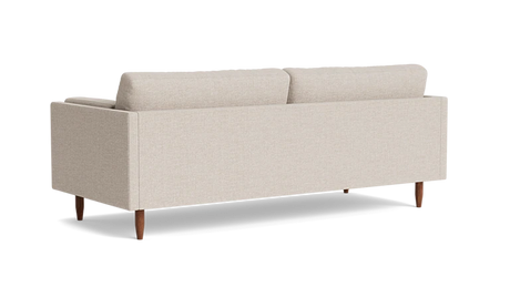 The Skinny Fat 85" Sofa Standard Depth is displayed from the back, showcasing its minimalist design with two plush cushions and wooden legs, all set against a plain black background.