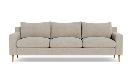 The Sloan Custom 3-Seat 95" Sofa, featuring a beige upholstery, square cushions, and wooden legs, is set against a plain black background. Its simple and modern design includes a straight back with armrests aligned at the same height as the back cushions.