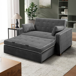 A modern living room showcases the Serta Monroe Full Size Convertible Sofa in gray, accented with white piping and spacious enough to convert into a sleeper. It comes with matching cushions and is set against green walls adorned by a potted plant. A lamp and bookshelf enhance the cozy ambiance.