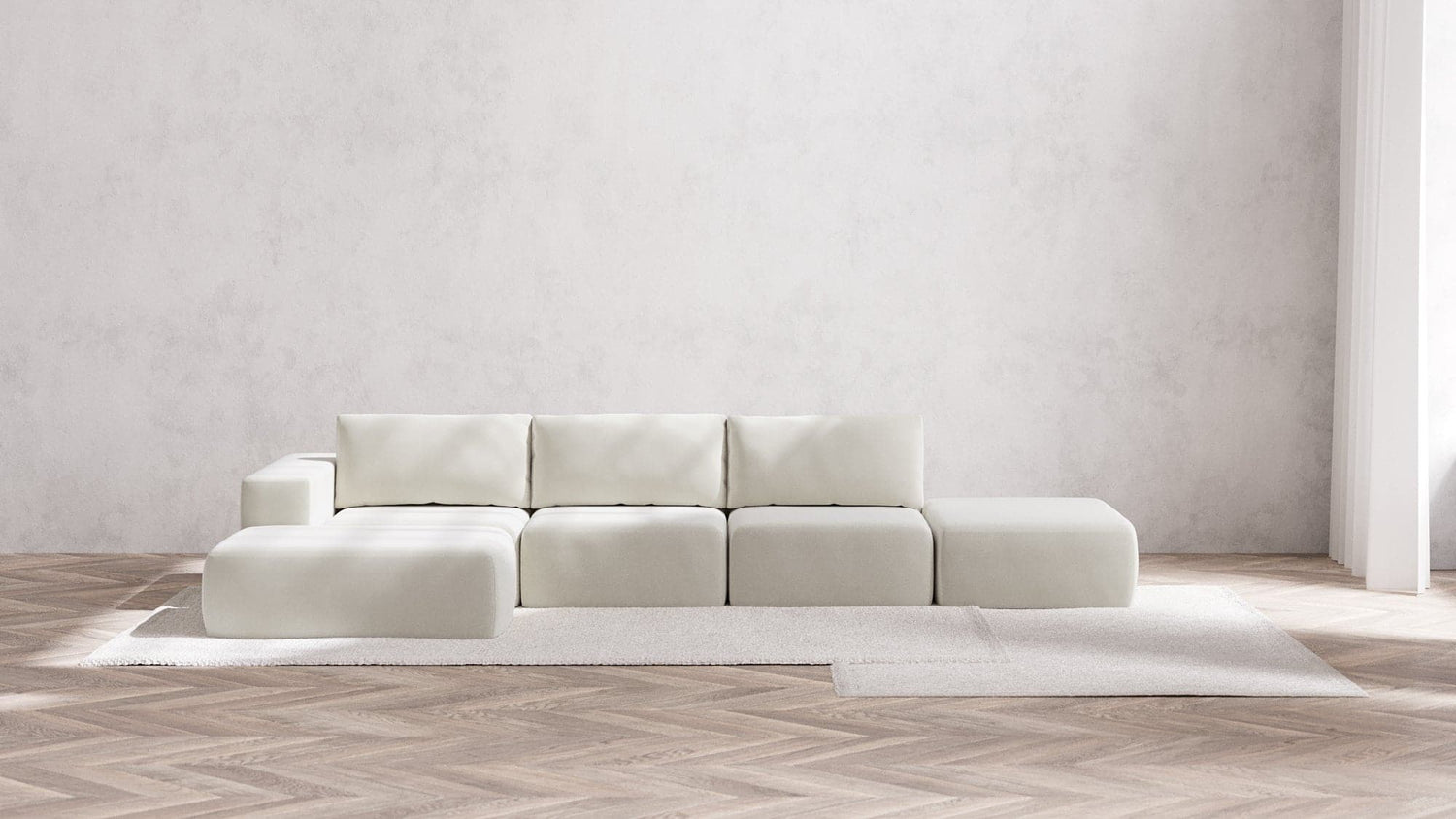 In a minimalist living room, the Modular 3-Seater Open-End Chaise Sectional in Boucle Aspen takes center stage atop a light area rug. The floor showcases a herringbone wood pattern, while the plain, light gray wall in the background enhances the airy and serene ambiance of the space.
