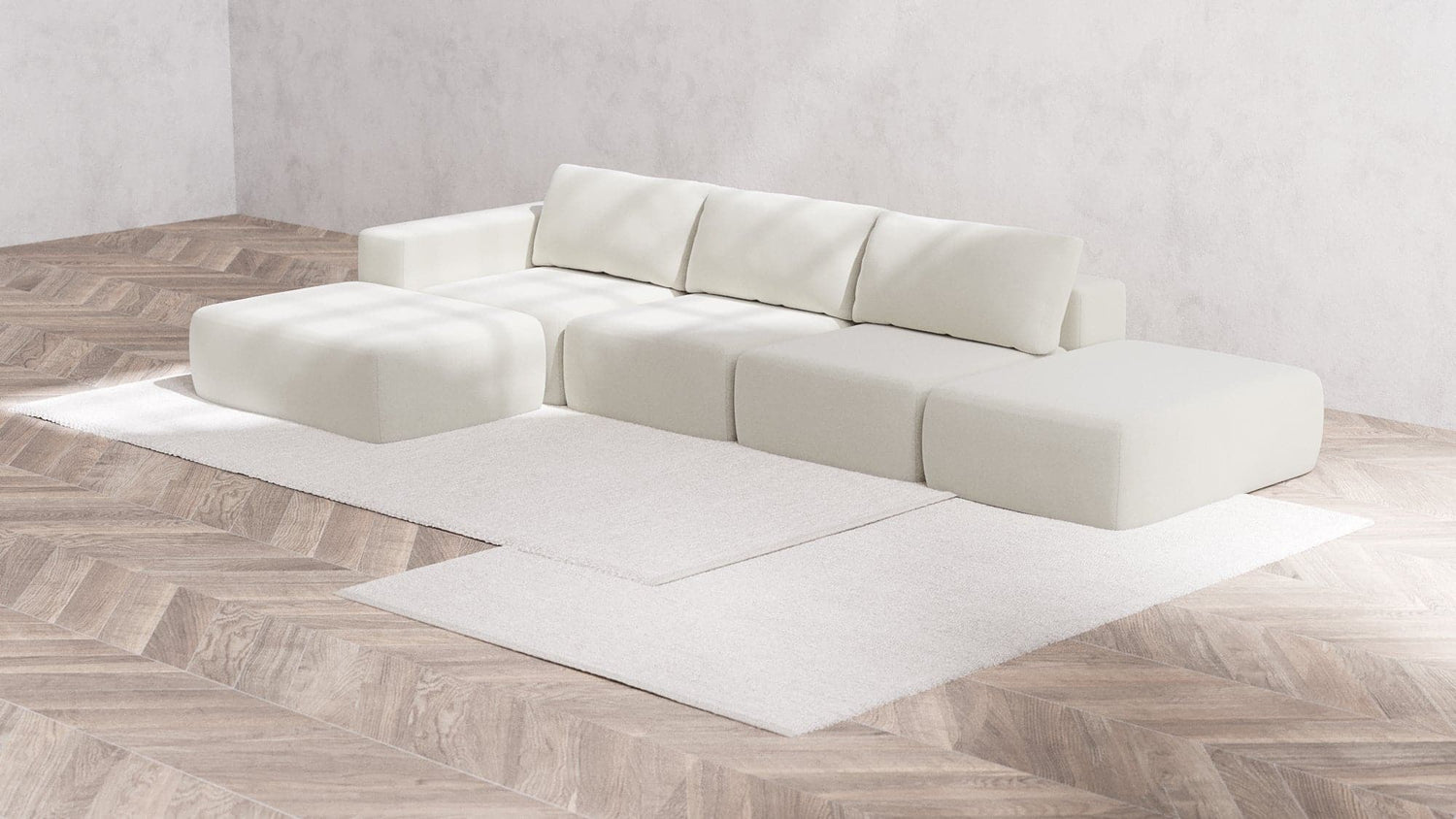 The Modular 3-Seater Open-End Chaise Sectional in Boucle, Aspen, with its modern and modular design featuring clean lines, is arranged in an L-shape on a light wood herringbone floor. Two white area rugs are layered underneath, creating a minimalist and serene living space.