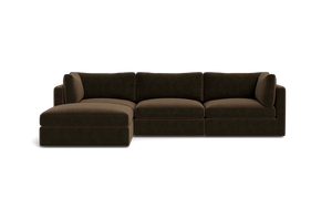 The Tatum Modular 3 Seat Chaise Sectional, featuring a large, dark brown design with cushioned seats and backrests, is displayed against a solid black background. It includes a chaise lounge on the left side, offering ample seating space.