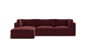 The Tatum Modular 3 Seat Chaise Sectional, upholstered in maroon, sits against a solid black background. It boasts plush cushions and a chaise lounge on the left side, providing a modern and comfortable seating option.