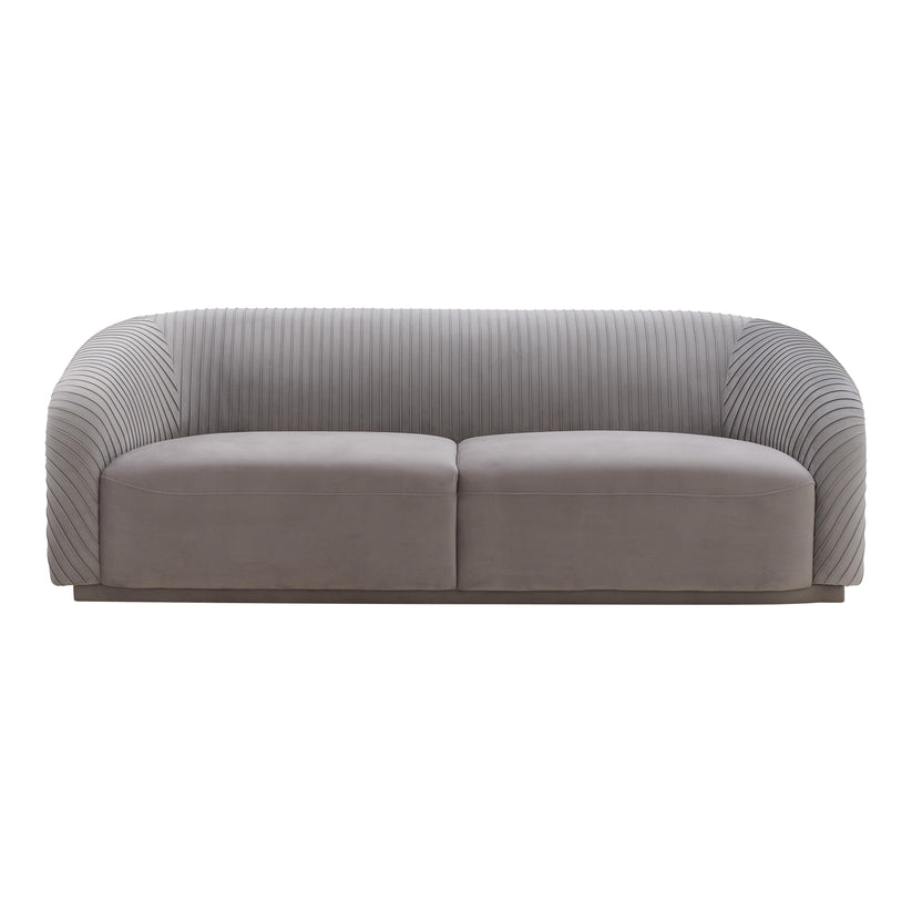 The Yara Pleated Velvet Sofa by Inspire Me! Home Decor features a gray upholstery with a ribbed texture on the back and sides. Its modern, rounded design and smooth cushions provide a clean and contemporary appearance.