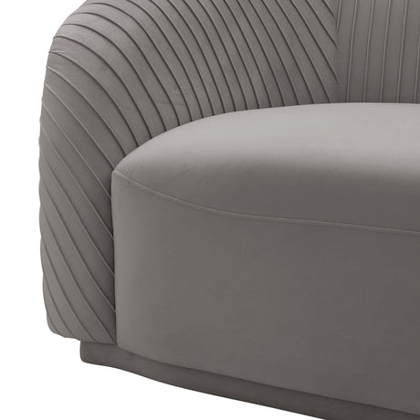 Close-up of the Yara Pleated Velvet Sofa by Inspire Me! Home Decor, showcasing its modern gray hue with textured pleating on the armrests and a smooth seat cushion. The design features a minimalist, curved shape that emphasizes contemporary style.