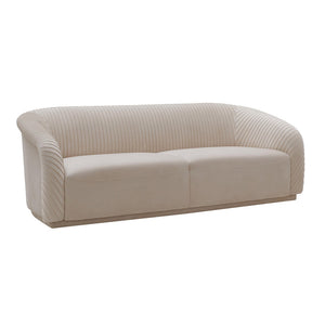 Introducing the Yara Pleated Velvet Sofa by Inspire Me! Home Decor: a beige, modern piece featuring curved arms and a ribbed backrest design. This sofa boasts a sleek, minimalist aesthetic on a flat base, perfect for contemporary living spaces.