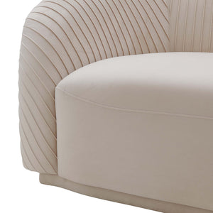 A detailed view of the Yara Pleated Velvet Sofa by Inspire Me! Home Decor, showcasing its cream color and rounded, cushioned backrest. The linear, ribbed texture on the sides enhances the elegance of its contemporary design.