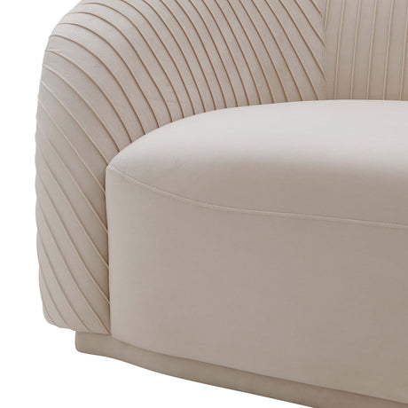 A detailed view of the Yara Pleated Velvet Sofa by Inspire Me! Home Decor, showcasing its cream color and rounded, cushioned backrest. The linear, ribbed texture on the sides enhances the elegance of its contemporary design.