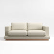 The Tidal Apartment 83" Sofa is a contemporary two-seater in beige, featuring plush cushions and a wooden base, presented against a simple light background.