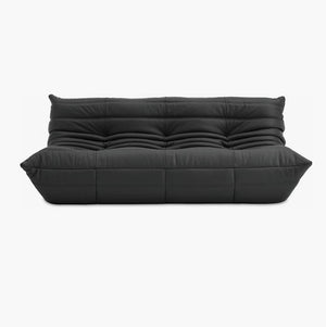 The Togo Sofa in Opera Leather boasts a sleek design in black leather, featuring a tufted pattern with deep cushions and an elegant modern aesthetic set against a plain white background.