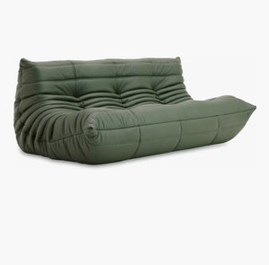 A Togo Sofa in Opera Leather, featuring a tufted design with a low profile and soft, rounded edges, upholstered in green leather or a similar material, set against a white background.