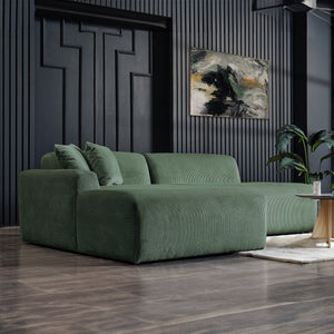 A modern living room showcases the Mar High-Quality Sectional Sofa on a wooden floor. A dark textured wall displays a vibrant abstract painting. A small round table and a plant enhance the decor, creating a cozy, contemporary atmosphere.