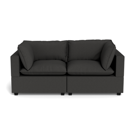 The Kova Pillow Cushion Sofa 86" is a modern dark gray fabric sofa with wide armrests, two large seat cushions, and two matching back cushions, shown from the front against a black background.